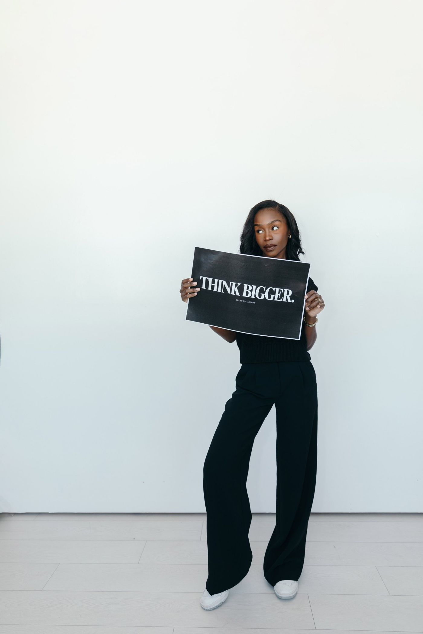 Ave holding a sign that reads Think Bigger